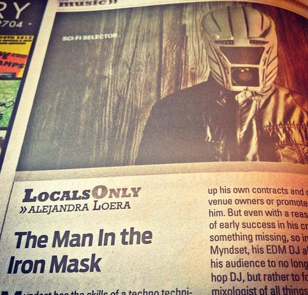A man wearing a helmet and mask, with a headline about "The Man in the Iron Mask."