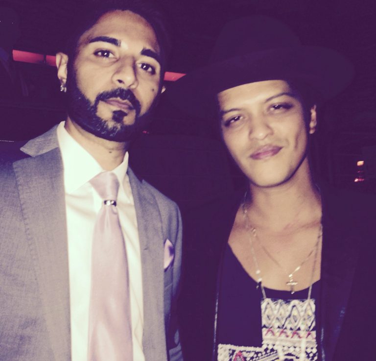 Jash Negandhi & Bruno Mars Jash in a suit and Bruno Mars in a hat and casual attire.