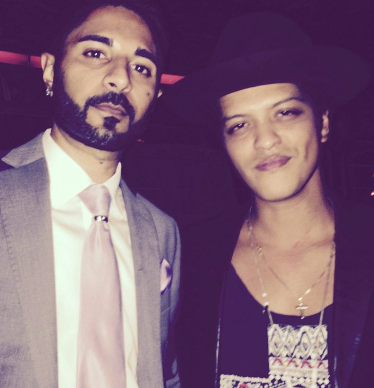 Jash in a suit and Bruno Mars in a hat and casual attire.