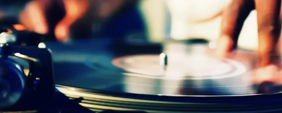 A close-up of a hand adjusting a vinyl record on a turntable.